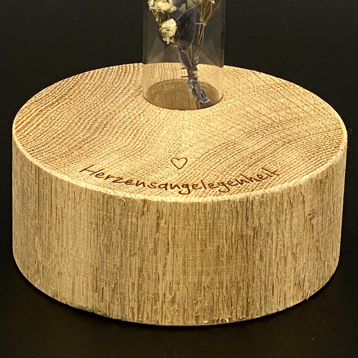 Diese Deko Block Vase aus Holz ist ein liebevolles Geschenk für besondere Menschen.
Der runde Holzblock trägt die Gravur „Herzensangelegenheiten“.
Im Loch des Blocks steckt ein Reagenzglas für zarte Trockenblumen.
Perfekt als kleine Aufmerksamkeit oder Herzensgruß.
Ein handgefertigtes Unikat voller Stil und Gefühl.