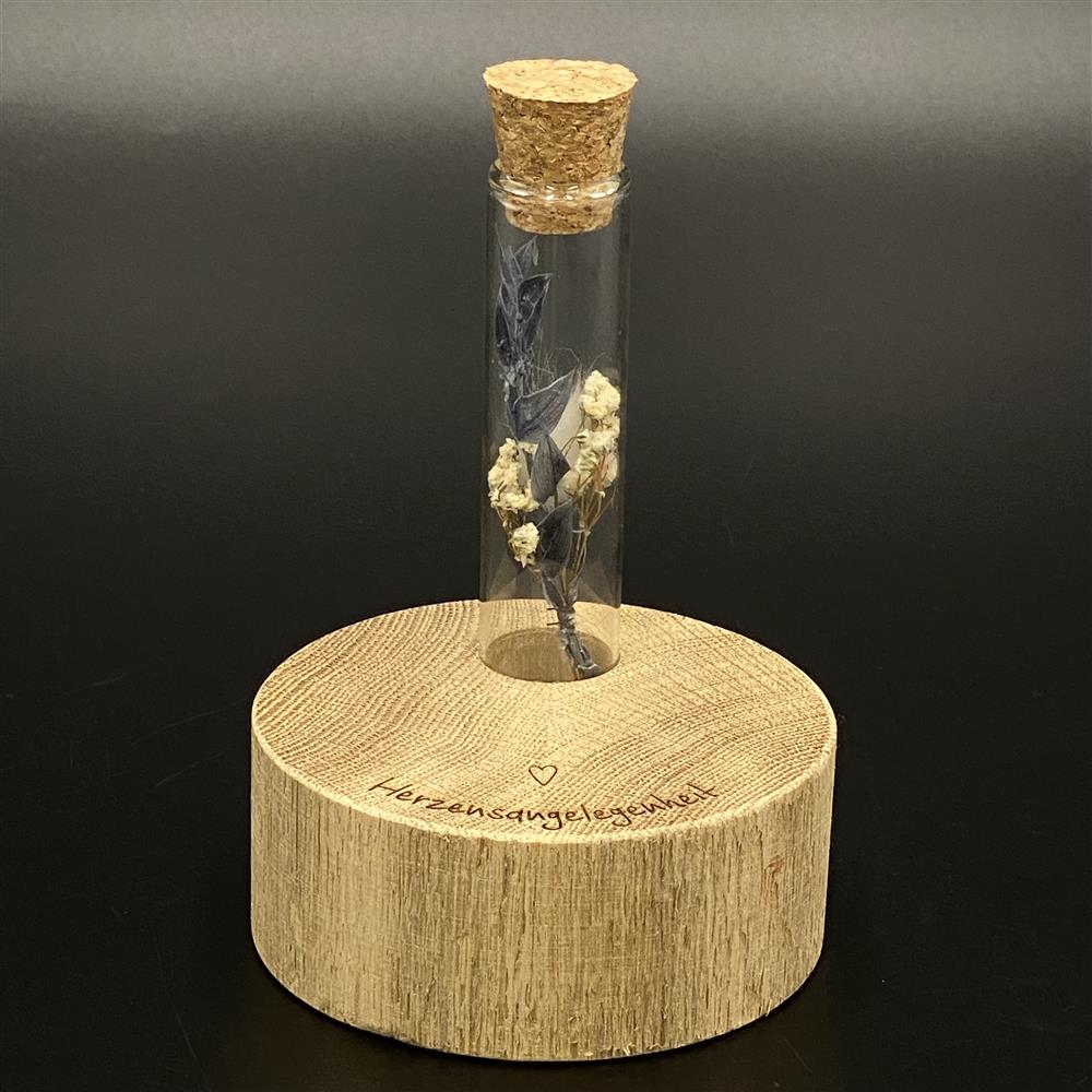 Diese Deko Block Vase aus Holz ist ein liebevolles Geschenk für besondere Menschen.
Der runde Holzblock trägt die Gravur „Herzensangelegenheiten“.
Im Loch des Blocks steckt ein Reagenzglas für zarte Trockenblumen.
Perfekt als kleine Aufmerksamkeit oder Herzensgruß.
Ein handgefertigtes Unikat voller Stil und Gefühl.