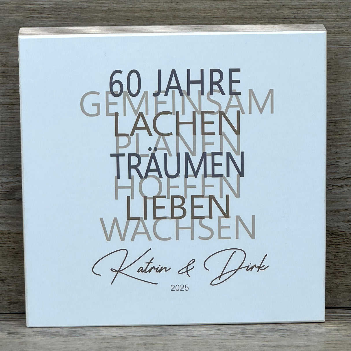 Feiere die Diamantene Hochzeit mit diesem stilvollen Geschenkset. Ein personalisierbarer Holzblock mit Aufschrift wie Lieben, Hoffen, Wachsen erinnert an 60 gemeinsame Jahre. Ein dekoratives Reagenzglas mit Holz-Zahl '60' eignet sich ideal für Gutscheine oder Geldgeschenke. Das Set wird in einer hochwertigen Geschenkbox mit dem Spruch „Der schönste Weg ist der Gemeinsame“ geliefert und ist ein einzigartiges Präsent für das Jubelpaar.