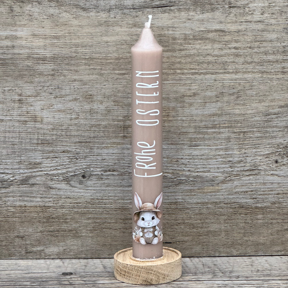 Diese weiße Stabkerze mit fröhlichem Osterhasen und Schriftzug „Frohe Ostern“ ist das perfekte Geschenk für Familie, Freunde oder Kinder – ideal als kleine Aufmerksamkeit zu Ostern. Optional mit Geschenkverpackung und Holzkerzenständer erhältlich. Sie bringt festliche Stimmung in jedes Zuhause und zaubert ein Lächeln auf die Gesichter deiner Liebsten. Dekorativ, hochwertig und liebevoll gestaltet. Ein kleines Geschenk voller Freude und Osterzauber.