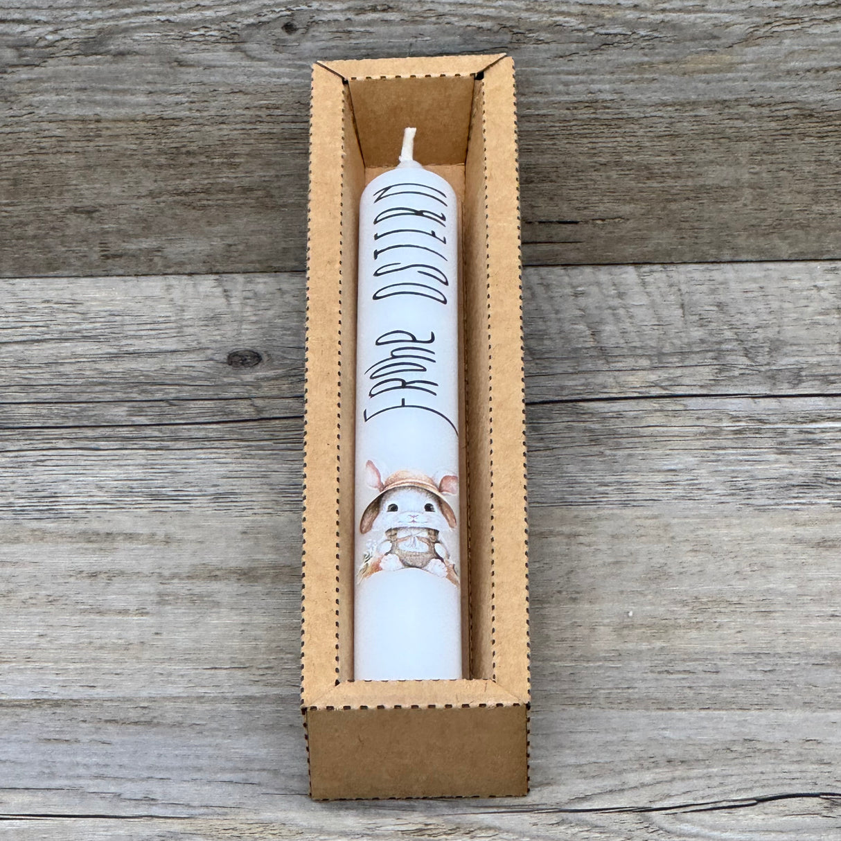 Diese weiße Stabkerze mit fröhlichem Osterhasen und Schriftzug „Frohe Ostern“ ist das perfekte Geschenk für Familie, Freunde oder Kinder – ideal als kleine Aufmerksamkeit zu Ostern. Optional mit Geschenkverpackung und Holzkerzenständer erhältlich. Sie bringt festliche Stimmung in jedes Zuhause und zaubert ein Lächeln auf die Gesichter deiner Liebsten. Dekorativ, hochwertig und liebevoll gestaltet. Ein kleines Geschenk voller Freude und Osterzauber.