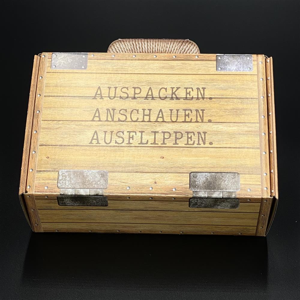 Hochwertiger Koffer aus Karton in edler Holzoptik, bedruckt mit „Auspacken, Anschauen, Ausflippen“. Perfekte Geschenkverpackung für Freunde, Familie oder Kollegen. Maße 23 x 15 x 8 cm, ideal für kleine Präsente und Überraschungen, die elegant und originell verpackt werden sollen.
