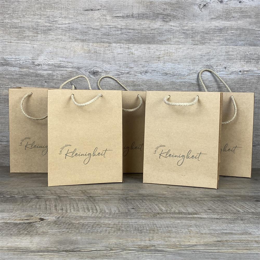 Dieses 5-teilige Set Geschenktüten besteht aus hochwertigem Kraftpapier (225 g/m²) mit praktischem Kordelgriff. Maße: 19 x 15 x 8 cm. Jede Tüte ist mit dem Aufdruck „Eine klitzekleine Kleinigkeit“ versehen – ideal, um kleinen Geschenken eine besondere Note zu verleihen.