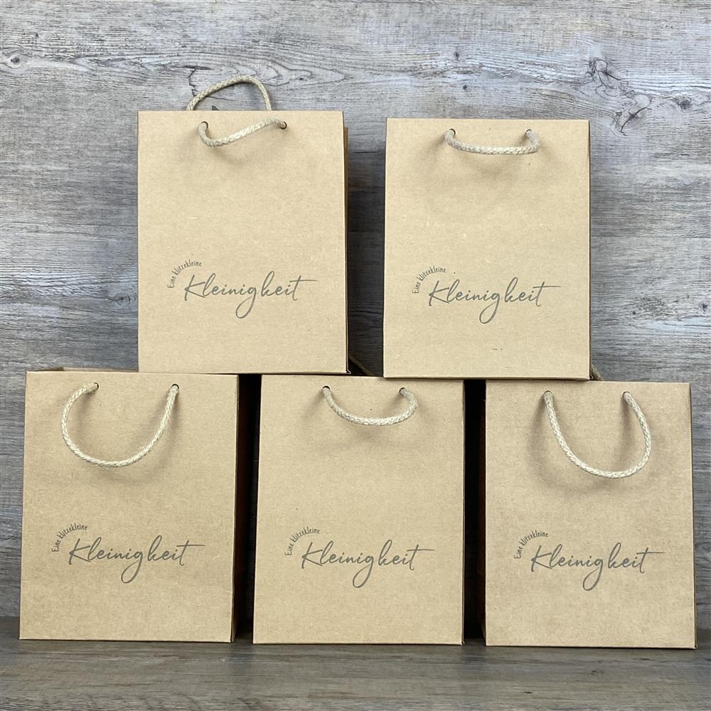 Dieses 5-teilige Set Geschenktüten besteht aus hochwertigem Kraftpapier (225 g/m²) mit praktischem Kordelgriff. Maße: 19 x 15 x 8 cm. Jede Tüte ist mit dem Aufdruck „Eine klitzekleine Kleinigkeit“ versehen – ideal, um kleinen Geschenken eine besondere Note zu verleihen.