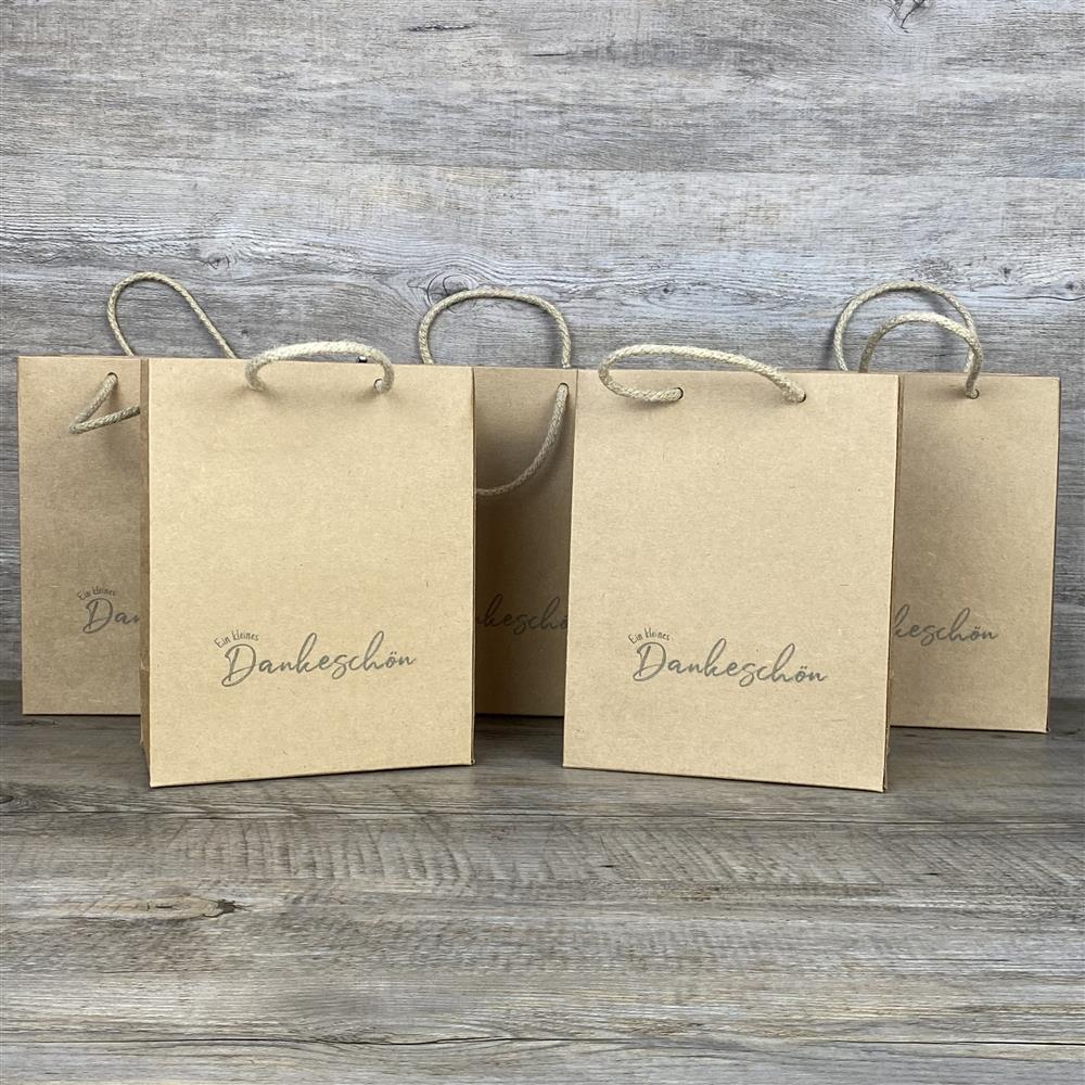 Set aus 5 Geschenktüten aus robustem Kraftpapier (225 g/m²) inklusive Kordelgriff. Größe: 19 x 15 x 8 cm. Die Tüten sind mit dem liebevollen Aufdruck „Ein kleines Dankeschön“ versehen und eignen sich hervorragend zum Verpacken kleiner Geschenke, Mitgebsel oder Überraschungen.