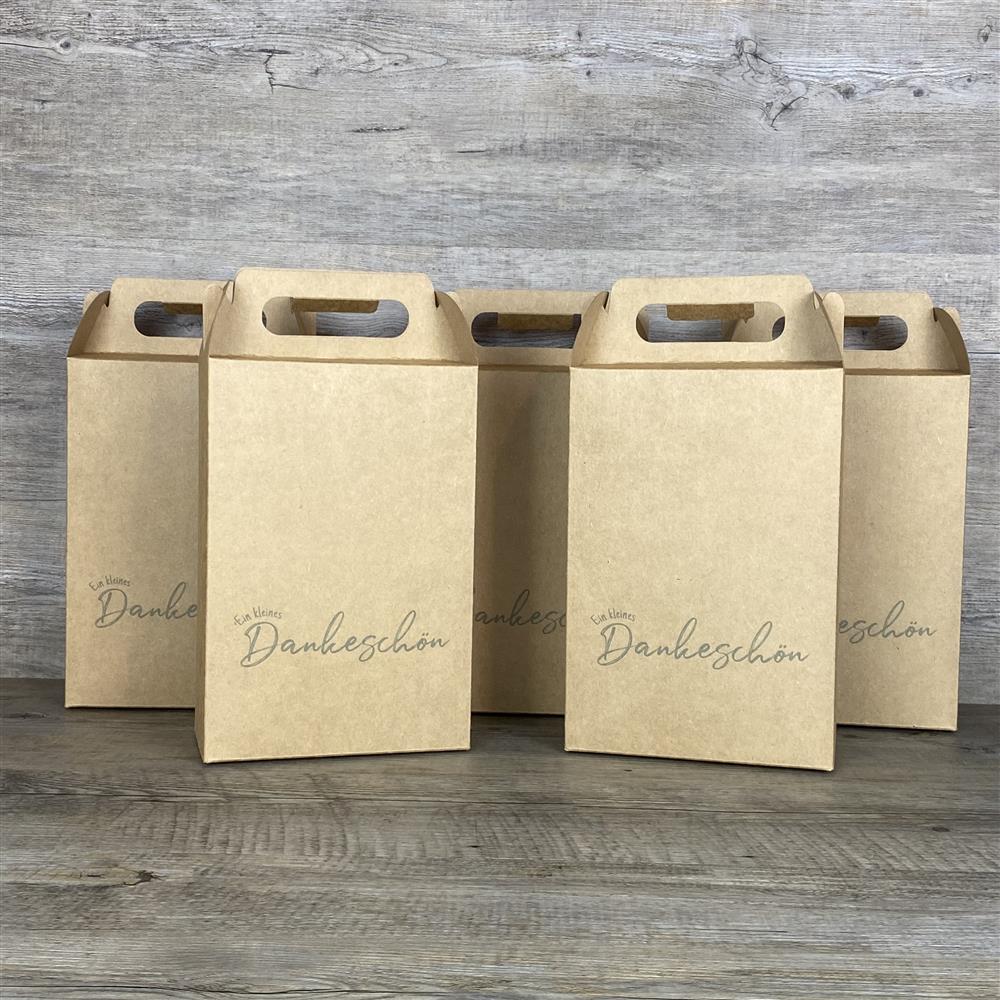 Giebelverpackung aus robustem Kraftkarton, 5 Stück im Set, Größe ca. 22 x 15 x 8 cm, Gesamthöhe mit Griff ca. 28 cm. Aufdruck: „Ein kleines Dankeschön“. Ideal als Geschenkverpackung für kleine Aufmerksamkeiten, Mitbringsel oder Weihnachtsgeschenke. Perfekt für Familie, Freunde oder Kollegen – stilvoll, nachhaltig und wiederverwendbar.