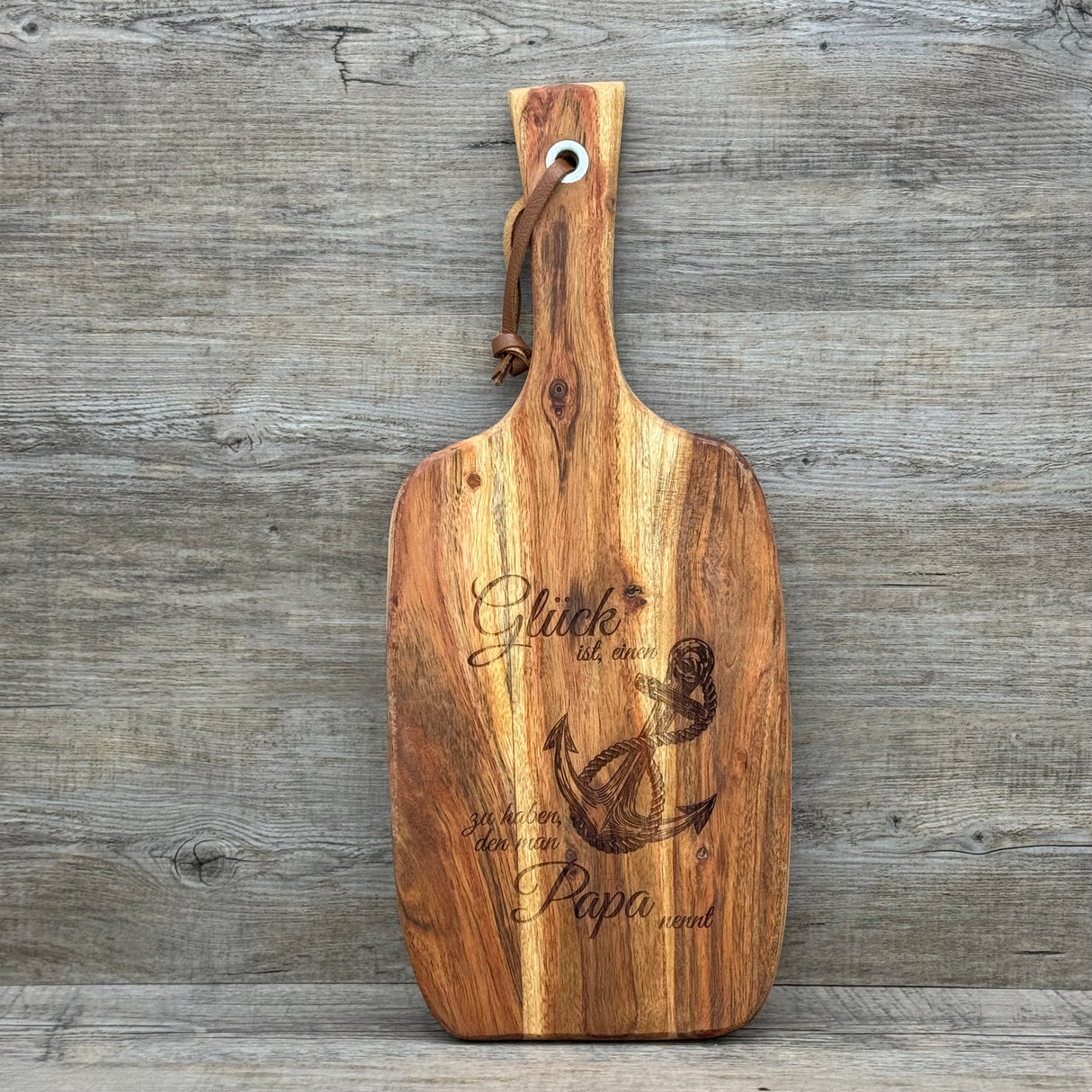 Dieses Servierbrett „Glück ist ein Anker“ aus massivem Akazienholz ist das perfekte Geschenk für Papa – ideal zum Vatertag, Geburtstag oder als liebevolle Überraschung zwischendurch. Die Lasergravur mit Anker und Spruch macht es zu einem persönlichen Unikat. Vielseitig nutzbar als Servier- oder Schneidebrett oder als dekoratives Highlight in der Küche. Praktisch mit Lederband zum Aufhängen. Ein emotionales Geschenk, das Herz und Wertschätzung zeigt.