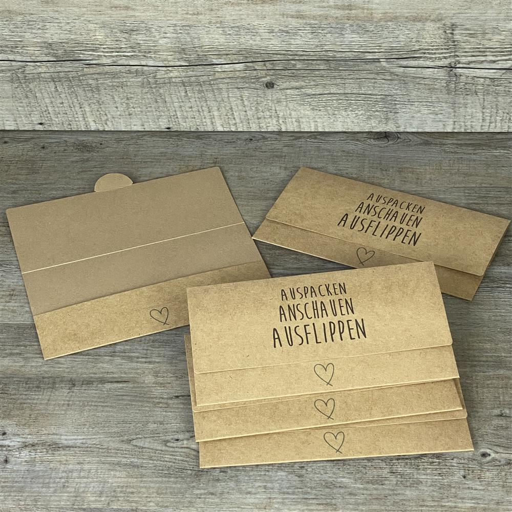 Verschenke Gutscheine auf besondere Weise mit diesem 5er-Set Kraftpapier-Verpackungen. Maße ca. 21,5 x 11 cm, passend für Gutscheine bis 21 x 10,5 cm, liebevoll gestalteter Aufdruck „Auspacken, Anschauen, Ausflippen“ mit Herzmotiv. Vielseitig einsetzbar für Geburtstage, Jubiläen, Hochzeiten oder kleine Überraschungen – stilvoll, nachhaltig und hochwertig.