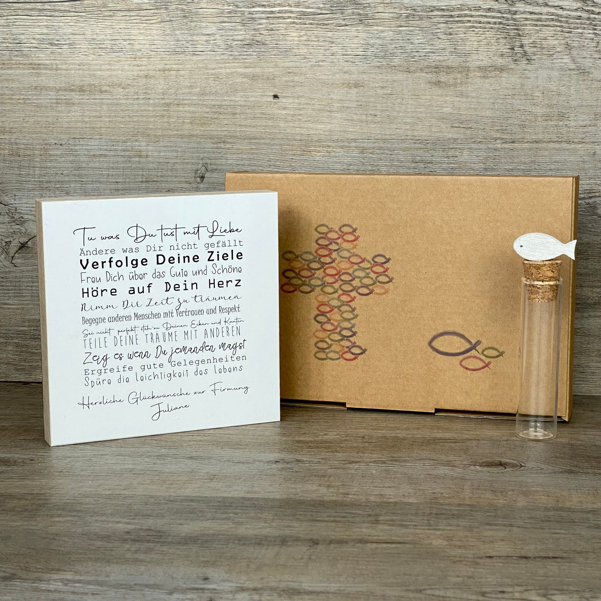 Dieses Geschenkset zur Firmung ist ein besonderes Präsent voller guter Wünsche und inspirierender Botschaften. Es enthält einen handgefertigten Wooden Block Art mit motivierenden Sprüchen wie „Tue was Du tust mit Liebe“ und „Spüre die Leichtigkeit des Lebens“, personalisierbar mit deinem Wunschnamen. Dazu gehört ein dekoratives Reagenzglas mit Korken und Deko-Fisch, ideal für Geldgeschenke oder Gutscheine. Alles ist geschmackvoll verpackt in einer hochwertigen Geschenkbox mit christlichen Motiven.