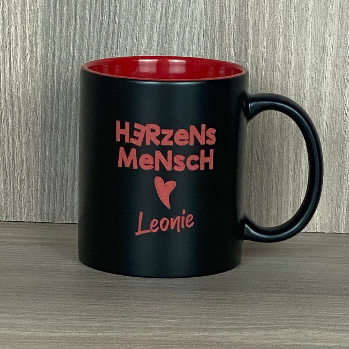 Diese personalisierte Keramik-Tasse „Herzensmensch“ mit schwarzer Außenseite und farbiger Innenseite ist ein liebevolles Geschenk für besondere Menschen. Mit Lasergravur „Herzensmensch“ inklusive Herzmotiv und deinem Wunschnamen wird sie zu einem einzigartigen Unikat. Fassungsvermögen 350 ml, Maße ca. Ø 8,2 × 9,6 cm, ideal für Kaffee, Tee oder Kakao. Perfekt für Zuhause, Büro oder als persönliche Aufmerksamkeit.
