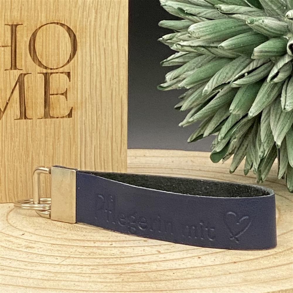 Blaues Leder-Schlüsselband mit Blindprägung ‚Pflegerin mit Herz‘ und Metallverschluss – Geschenkidee für Pflegekräfte.