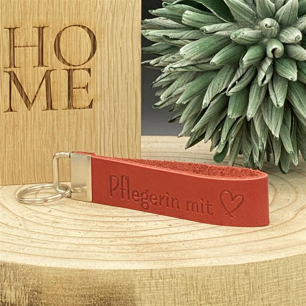 Rotes Leder-Schlüsselband mit Blindprägung ‚Pflegerin mit Herz‘ und Metallverschluss – Geschenkidee für Pflegekräfte.