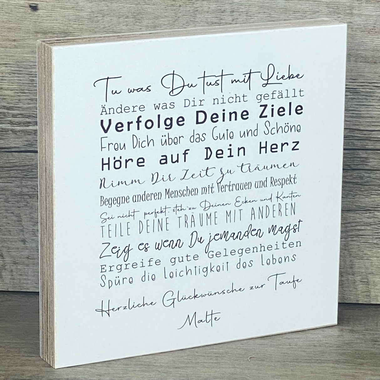 Ein liebevolles Geschenkset zur Taufe – handgefertigt und personalisierbar mit dem Namen des Kindes. Enthalten ist ein Wooden Block Art „Taufe“ (15 x 15 x 2,2 cm) mit inspirierenden Botschaften wie Tue was Du tust mit Liebe, Freu Dich über das Gute und Schöne, Hör auf Dein Herz. Dazu ein Reagenzglas mit Korken und Deko-Fisch (13 x 2,5 cm), ideal für Geldgeschenke oder Gutscheine. Verpackt in einer stilvollen Geschenkbox mit christlichen Motiven, wählbar als Fisch oder Kreuz. Nachhaltig produziert, jedes Stü