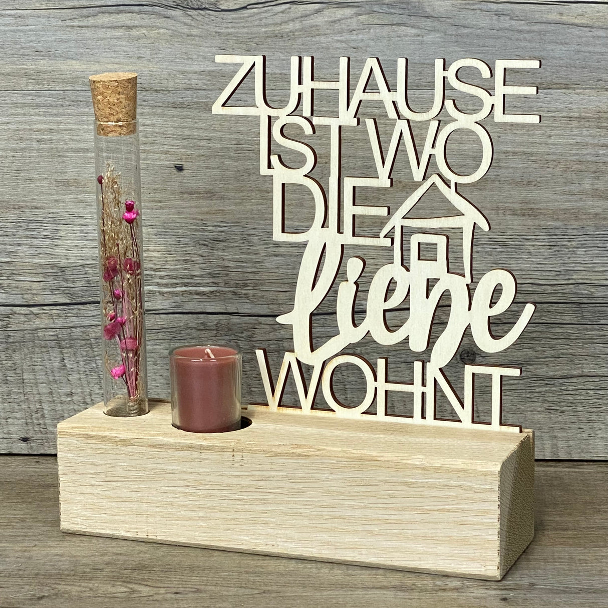 Variante 2 – Design & Details
Hochwertiger Deko-Aufsteller Deluxe „Zuhause, ist wo die Liebe wohnt“ aus Eichenholz mit 3 mm dickem Pappelholz-Schriftzug.
Perfekt personalisierbar als Geschenk für Lieblingsmenschen oder zur Einweihung des neuen Zuhauses.
Mit Reagenzglas, Trockenblumen und Kerze – romantisches Highlight für jeden Wohnraum.
Maße: Aufsteller ca. 20 x 6 x 5 cm, Schriftzug ca. 15 x 17 cm, Geschenkverpackung ca. 23 x 15 x 4,5 cm.
Ein stilvolles und dekoratives Geschenk für Einzug, Hochzeitstag ode
