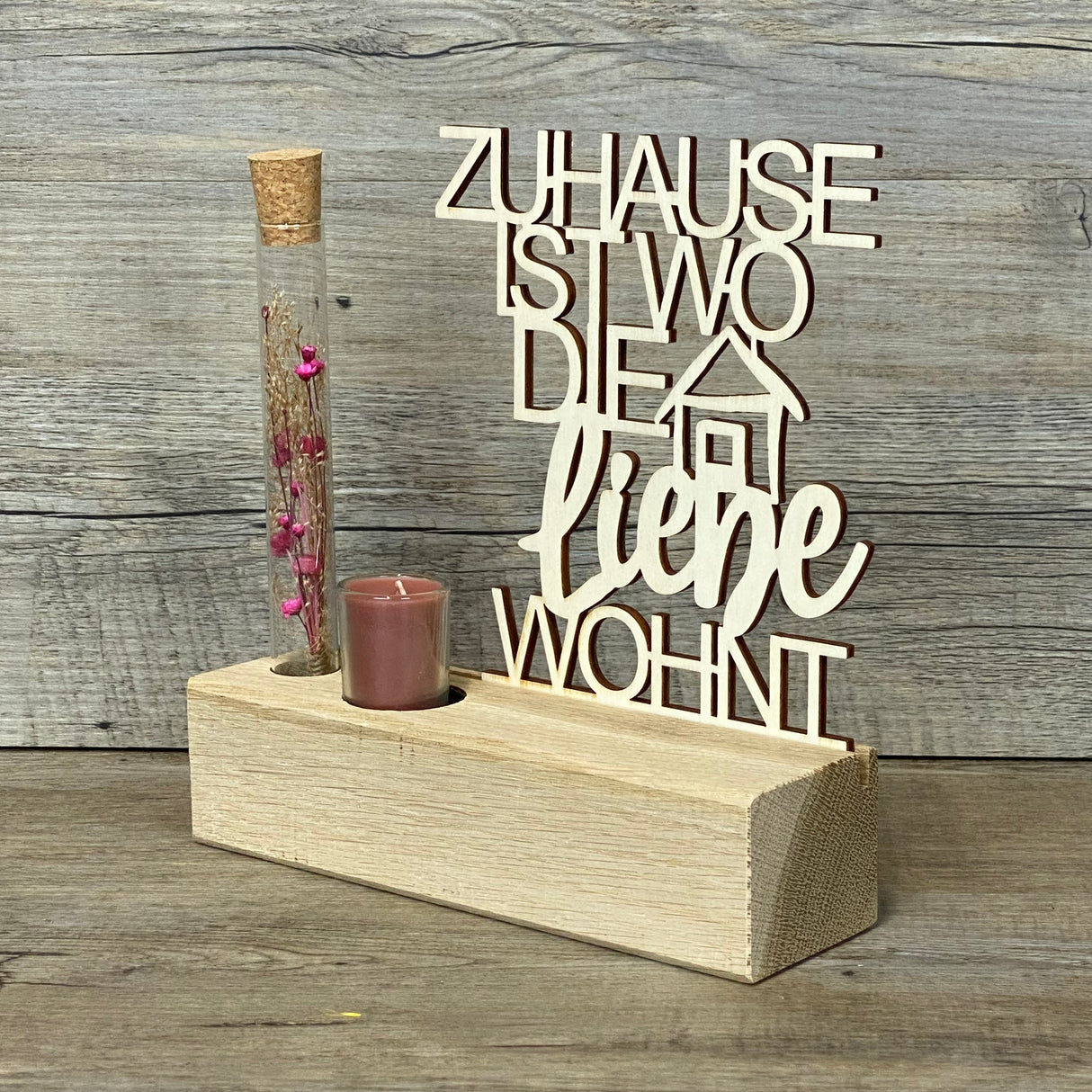 Variante 2 – Design & Details
Hochwertiger Deko-Aufsteller Deluxe „Zuhause, ist wo die Liebe wohnt“ aus Eichenholz mit 3 mm dickem Pappelholz-Schriftzug.
Perfekt personalisierbar als Geschenk für Lieblingsmenschen oder zur Einweihung des neuen Zuhauses.
Mit Reagenzglas, Trockenblumen und Kerze – romantisches Highlight für jeden Wohnraum.
Maße: Aufsteller ca. 20 x 6 x 5 cm, Schriftzug ca. 15 x 17 cm, Geschenkverpackung ca. 23 x 15 x 4,5 cm.
Ein stilvolles und dekoratives Geschenk für Einzug, Hochzeitstag ode