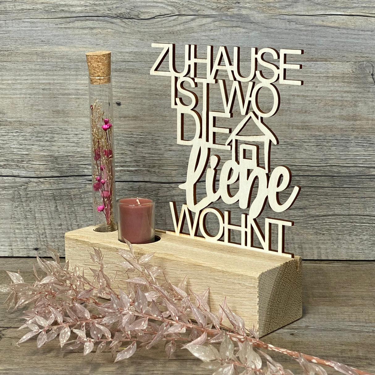 Variante 2 – Design & Details
Hochwertiger Deko-Aufsteller Deluxe „Zuhause, ist wo die Liebe wohnt“ aus Eichenholz mit 3 mm dickem Pappelholz-Schriftzug.
Perfekt personalisierbar als Geschenk für Lieblingsmenschen oder zur Einweihung des neuen Zuhauses.
Mit Reagenzglas, Trockenblumen und Kerze – romantisches Highlight für jeden Wohnraum.
Maße: Aufsteller ca. 20 x 6 x 5 cm, Schriftzug ca. 15 x 17 cm, Geschenkverpackung ca. 23 x 15 x 4,5 cm.
Ein stilvolles und dekoratives Geschenk für Einzug, Hochzeitstag ode