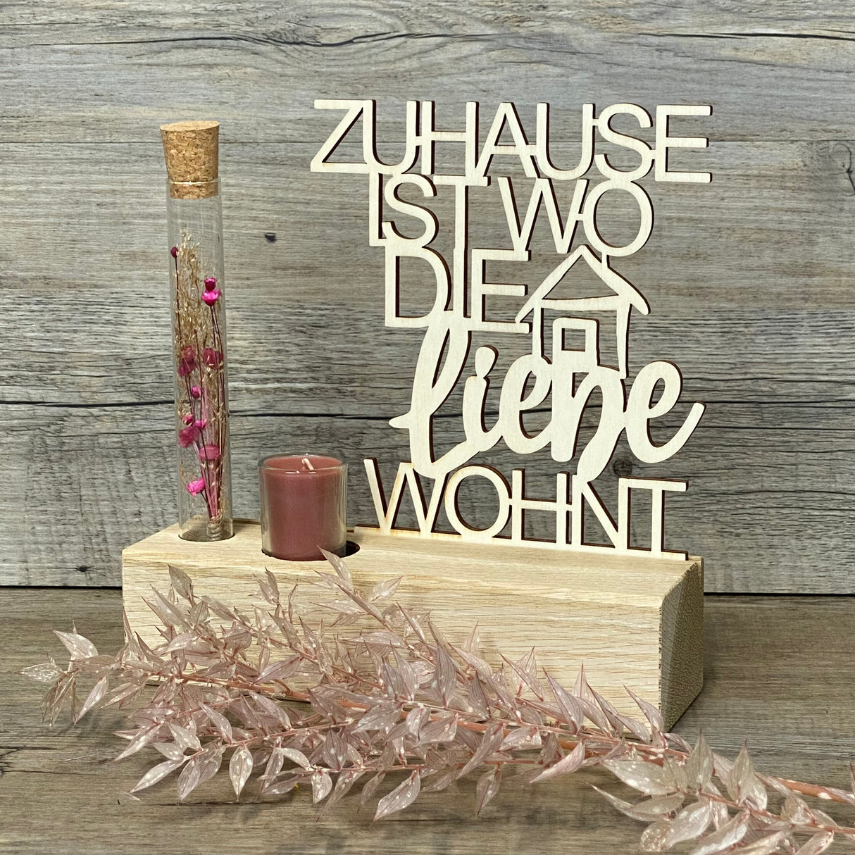 Variante 2 – Design & Details
Hochwertiger Deko-Aufsteller Deluxe „Zuhause, ist wo die Liebe wohnt“ aus Eichenholz mit 3 mm dickem Pappelholz-Schriftzug.
Perfekt personalisierbar als Geschenk für Lieblingsmenschen oder zur Einweihung des neuen Zuhauses.
Mit Reagenzglas, Trockenblumen und Kerze – romantisches Highlight für jeden Wohnraum.
Maße: Aufsteller ca. 20 x 6 x 5 cm, Schriftzug ca. 15 x 17 cm, Geschenkverpackung ca. 23 x 15 x 4,5 cm.
Ein stilvolles und dekoratives Geschenk für Einzug, Hochzeitstag ode
