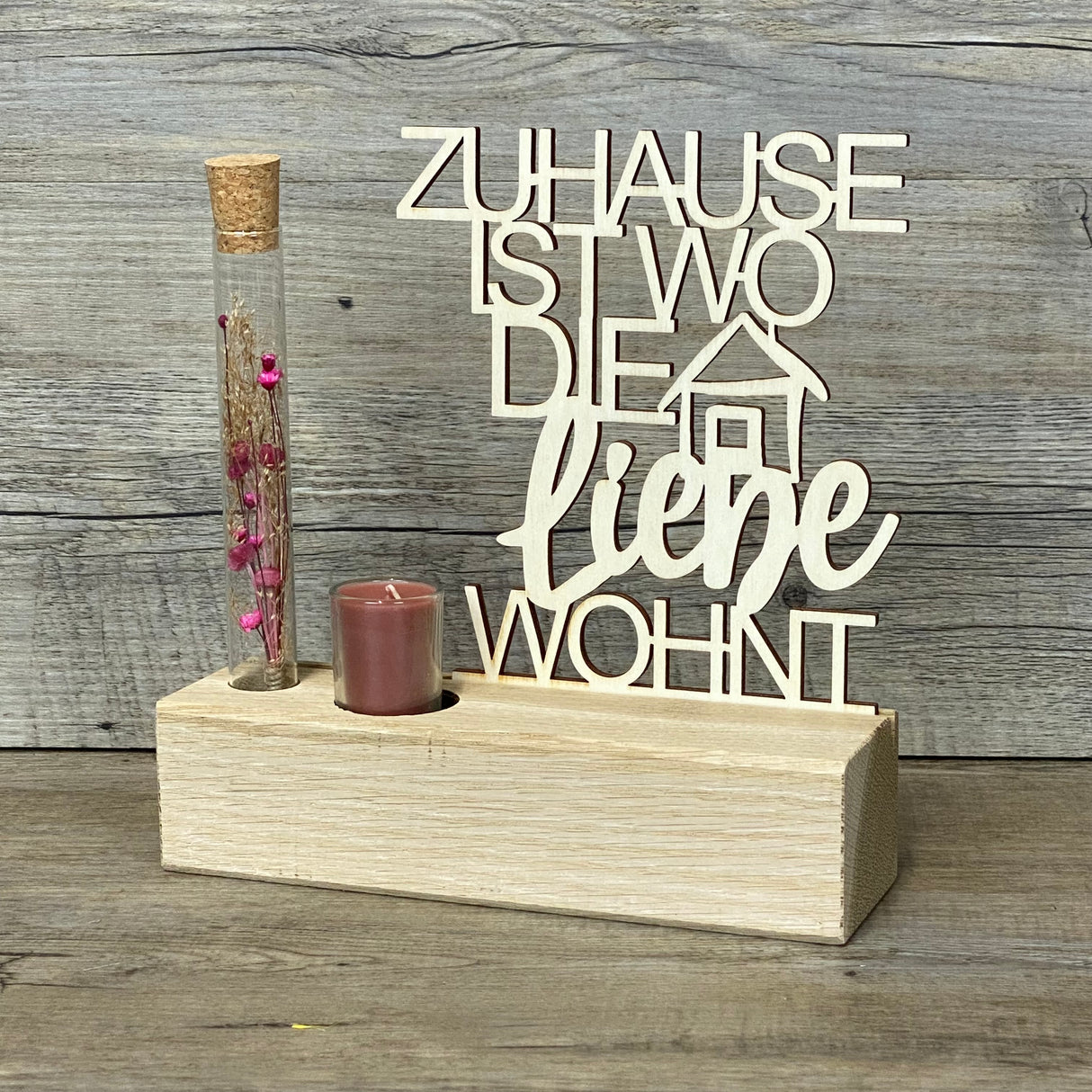 Variante 2 – Design & Details
Hochwertiger Deko-Aufsteller Deluxe „Zuhause, ist wo die Liebe wohnt“ aus Eichenholz mit 3 mm dickem Pappelholz-Schriftzug.
Perfekt personalisierbar als Geschenk für Lieblingsmenschen oder zur Einweihung des neuen Zuhauses.
Mit Reagenzglas, Trockenblumen und Kerze – romantisches Highlight für jeden Wohnraum.
Maße: Aufsteller ca. 20 x 6 x 5 cm, Schriftzug ca. 15 x 17 cm, Geschenkverpackung ca. 23 x 15 x 4,5 cm.
Ein stilvolles und dekoratives Geschenk für Einzug, Hochzeitstag ode