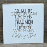 Feiere die Diamantene Hochzeit mit diesem stilvollen Geschenkset. Ein personalisierbarer Holzblock mit Aufschrift wie Lieben, Hoffen, Wachsen erinnert an 60 gemeinsame Jahre. Ein dekoratives Reagenzglas mit Holz-Zahl '60' eignet sich ideal für Gutscheine oder Geldgeschenke. Das Set wird in einer hochwertigen Geschenkbox mit dem Spruch „Der schönste Weg ist der Gemeinsame“ geliefert und ist ein einzigartiges Präsent für das Jubelpaar.
