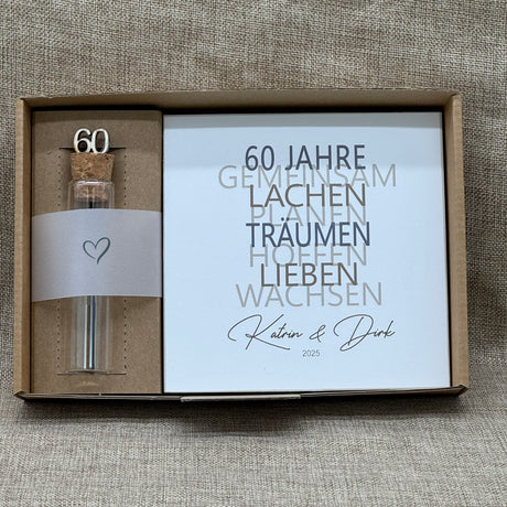 Feiere die Diamantene Hochzeit mit diesem stilvollen Geschenkset. Ein personalisierbarer Holzblock mit Aufschrift wie Lieben, Hoffen, Wachsen erinnert an 60 gemeinsame Jahre. Ein dekoratives Reagenzglas mit Holz-Zahl '60' eignet sich ideal für Gutscheine oder Geldgeschenke. Das Set wird in einer hochwertigen Geschenkbox mit dem Spruch „Der schönste Weg ist der Gemeinsame“ geliefert und ist ein einzigartiges Präsent für das Jubelpaar.
