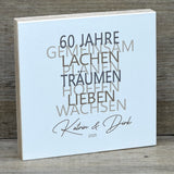 Dieses liebevolle Geschenkset zum 60. Hochzeitstag, der Diamantenen Hochzeit, besteht aus einem handgefertigten Holzblock mit inspirierenden Worten wie Lachen, Lieben und Wachsen. Auf Wunsch kann der Block mit Namen und Datum personalisiert werden. Dazu gibt es ein dekoratives Reagenzglas mit Holz-Zahl '60' für Geldgeschenke oder Gutscheine. Alles ist stilvoll verpackt in einer Geschenkbox mit Aufdruck „Der schönste Weg ist der Gemeinsame“.
