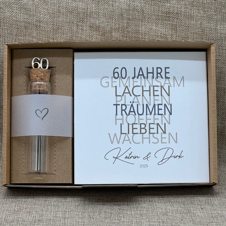 Dieses liebevolle Geschenkset zum 60. Hochzeitstag, der Diamantenen Hochzeit, besteht aus einem handgefertigten Holzblock mit inspirierenden Worten wie Lachen, Lieben und Wachsen. Auf Wunsch kann der Block mit Namen und Datum personalisiert werden. Dazu gibt es ein dekoratives Reagenzglas mit Holz-Zahl '60' für Geldgeschenke oder Gutscheine. Alles ist stilvoll verpackt in einer Geschenkbox mit Aufdruck „Der schönste Weg ist der Gemeinsame“.
