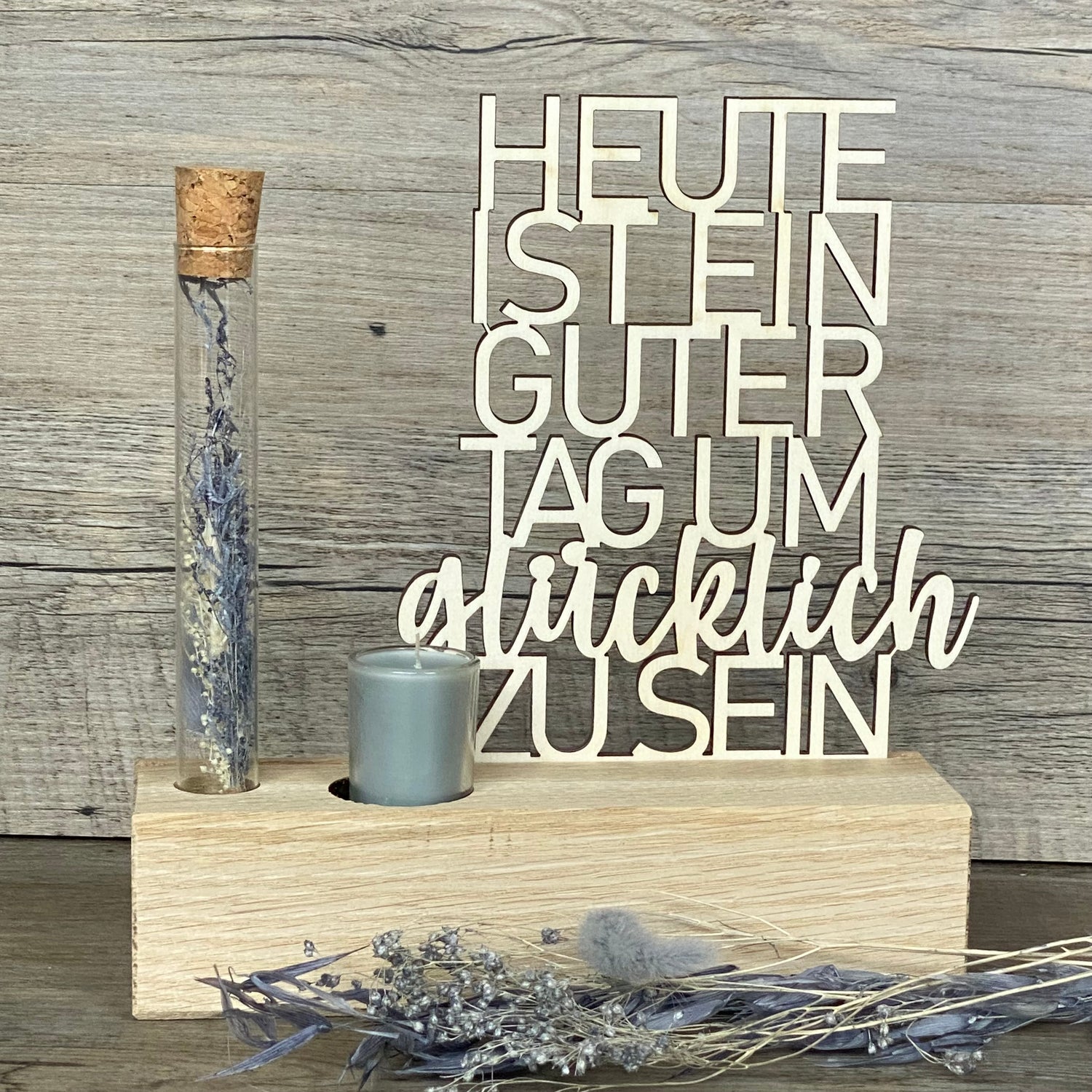 Deko Aufsteller Deluxe „Heute ist ein guter Tag um glücklich zu sein“ – das perfekte Geschenk für deine Lieblingsmenschen.  
Hochwertiger Aufsteller aus Eichenholz mit Schriftzug aus 3 mm Pappelholz.  
Inklusive Reagenzglas mit Trockenblumen und Kerze – wählbar in Blau oder Rot.  
Maße: Aufsteller ca. 20 x 6 x 5 cm, Geschenkverpackung ca. 25 x 20 x 7 cm.  
Personalisierbar mit Namen, Daten oder Koordinaten für ein einzigartiges Unikat.
