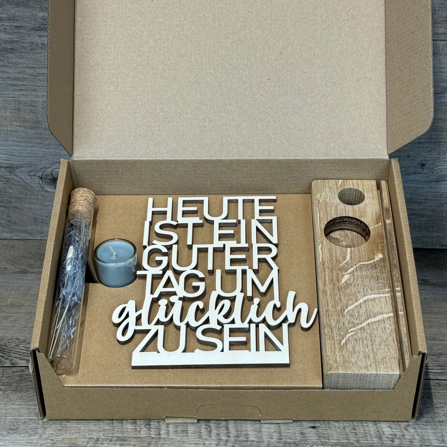 Der Deko Aufsteller Deluxe „Heute ist ein guter Tag um glücklich zu sein“ ist ein wunderschöner Blickfang für jede Wohnung.  
Aus Eichenholz gefertigt, Schriftzug aus 3 mm Pappelholz, mit Reagenzglas voller Trockenblumen und Kerze.  
Maße: ca. 20 x 6 x 5 cm, Geschenkverpackung ca. 25 x 20 x 7 cm, Trockenblumen und Kerze wählbar in Blau oder Rot.  
Personalisierbar mit Namen, Daten oder Koordinaten für ein einzigartiges, persönliches Geschenk.  
Perfekt als Geburtstags-, Hochzeits- oder Verlobungsgeschenk fü