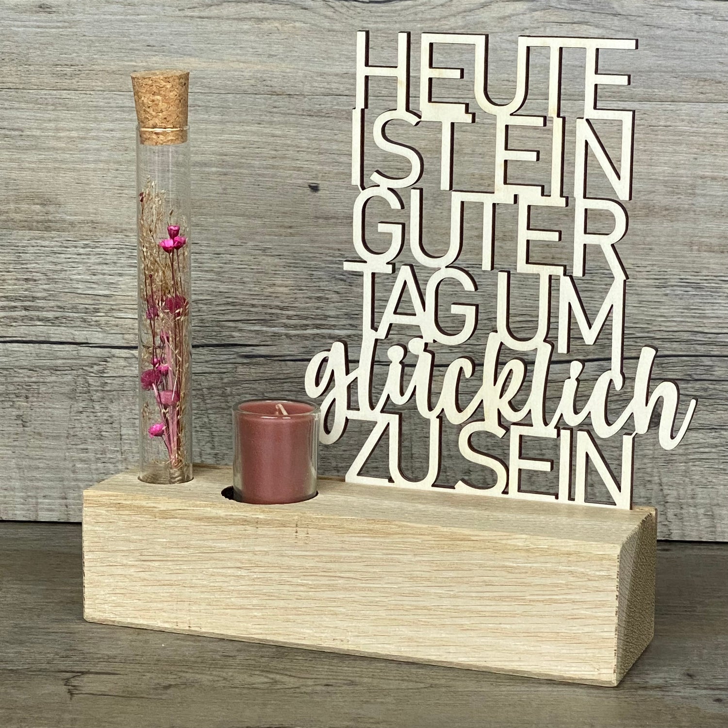 Verschenke Freude mit dem Deko Aufsteller Deluxe „Heute ist ein guter Tag um glücklich zu sein“.  
Gefertigt aus hochwertigem Eichenholz, Schriftzug aus Pappelholz, inklusive Reagenzglas mit Trockenblumen und Kerze.  
Größe Aufsteller: ca. 20 x 6 x 5 cm, Schriftzug ca. 15 x 18 cm, Geschenkverpackung ca. 25 x 20 x 7 cm.  
Trockenblumen und Kerze in Blau oder Rot erhältlich – Naturprodukt, Abweichungen möglich.  
Personalisierbar mit Namen, Datum oder Koordinaten – ein individuelles Geschenk für jeden Anlass.