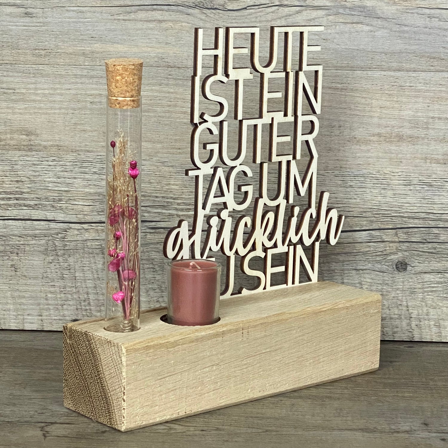 Verschenke Freude mit dem Deko Aufsteller Deluxe „Heute ist ein guter Tag um glücklich zu sein“.  
Gefertigt aus hochwertigem Eichenholz, Schriftzug aus Pappelholz, inklusive Reagenzglas mit Trockenblumen und Kerze.  
Größe Aufsteller: ca. 20 x 6 x 5 cm, Schriftzug ca. 15 x 18 cm, Geschenkverpackung ca. 25 x 20 x 7 cm.  
Trockenblumen und Kerze in Blau oder Rot erhältlich – Naturprodukt, Abweichungen möglich.  
Personalisierbar mit Namen, Datum oder Koordinaten – ein individuelles Geschenk für jeden Anlass.