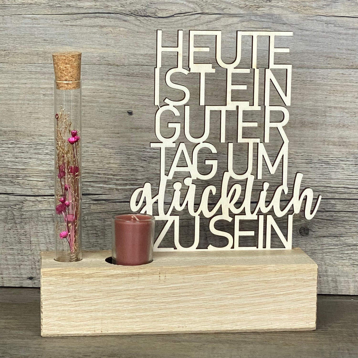 Verschenke Freude mit dem Deko Aufsteller Deluxe „Heute ist ein guter Tag um glücklich zu sein“.  
Gefertigt aus hochwertigem Eichenholz, Schriftzug aus Pappelholz, inklusive Reagenzglas mit Trockenblumen und Kerze.  
Größe Aufsteller: ca. 20 x 6 x 5 cm, Schriftzug ca. 15 x 18 cm, Geschenkverpackung ca. 25 x 20 x 7 cm.  
Trockenblumen und Kerze in Blau oder Rot erhältlich – Naturprodukt, Abweichungen möglich.  
Personalisierbar mit Namen, Datum oder Koordinaten – ein individuelles Geschenk für jeden Anlass.