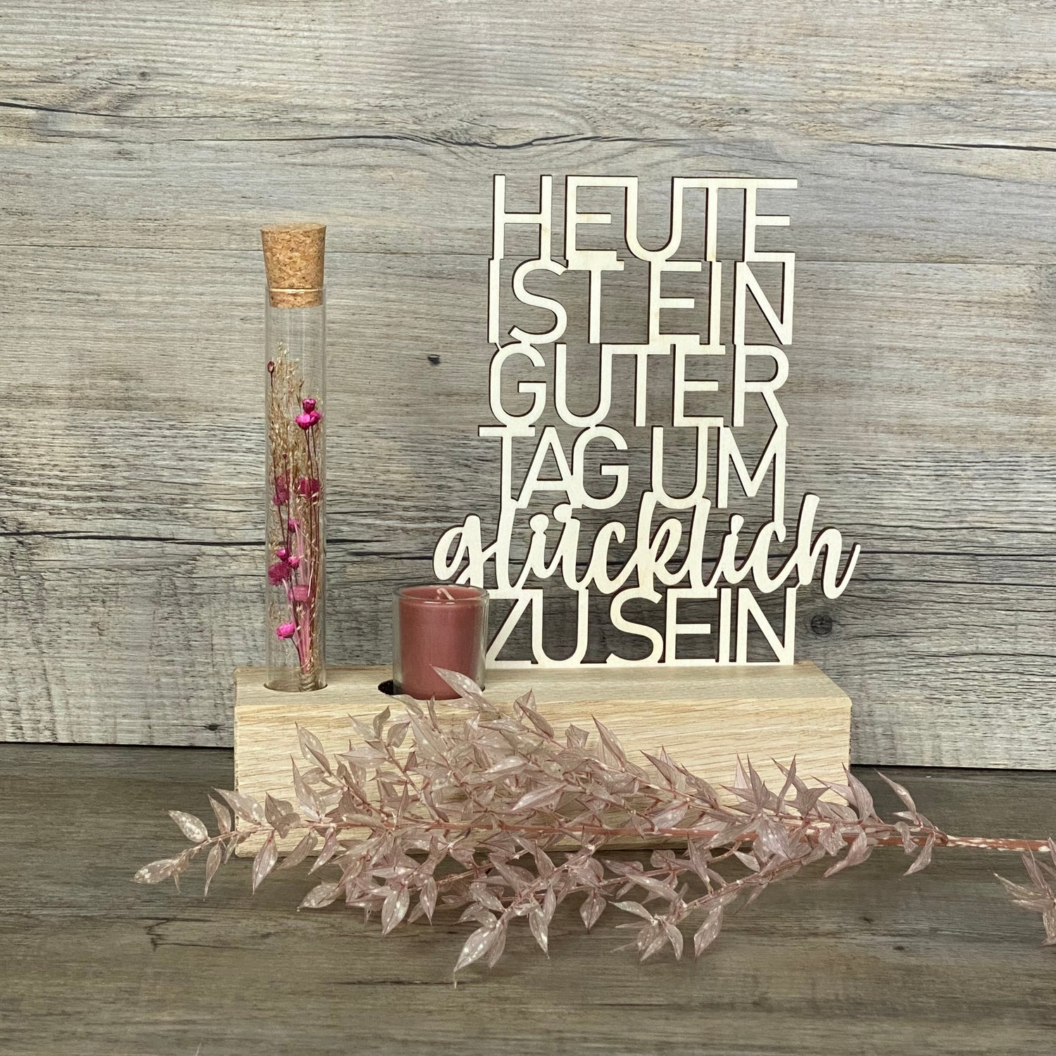 Der Deko Aufsteller Deluxe „Heute ist ein guter Tag um glücklich zu sein“ ist ein wunderschöner Blickfang für jede Wohnung.  
Aus Eichenholz gefertigt, Schriftzug aus 3 mm Pappelholz, mit Reagenzglas voller Trockenblumen und Kerze.  
Maße: ca. 20 x 6 x 5 cm, Geschenkverpackung ca. 25 x 20 x 7 cm, Trockenblumen und Kerze wählbar in Blau oder Rot.  
Personalisierbar mit Namen, Daten oder Koordinaten für ein einzigartiges, persönliches Geschenk.  
Perfekt als Geburtstags-, Hochzeits- oder Verlobungsgeschenk fü