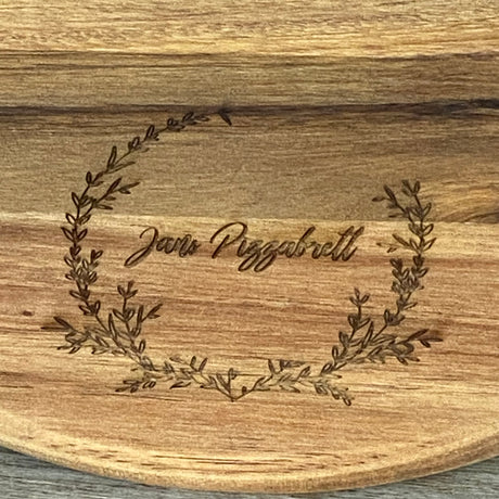 Dieses personalisierte runde Servierbrett aus FSC-zertifiziertem Akazienholz ist ein perfektes Geschenk für Familie oder Freunde. Mit individueller Gravur wie „Finger weg von [Name]’s Pizza“ wird es zu einem einzigartigen Küchenhighlight. Ideal zum Servieren von Pizza, Tapas oder Käseplatten bei gemütlichen Abenden. Das langlebige, antibakterielle Holz und der praktische Griff sorgen für Funktionalität und Stil. Ein dekoratives und praktisches Präsent für jeden Anlass.
